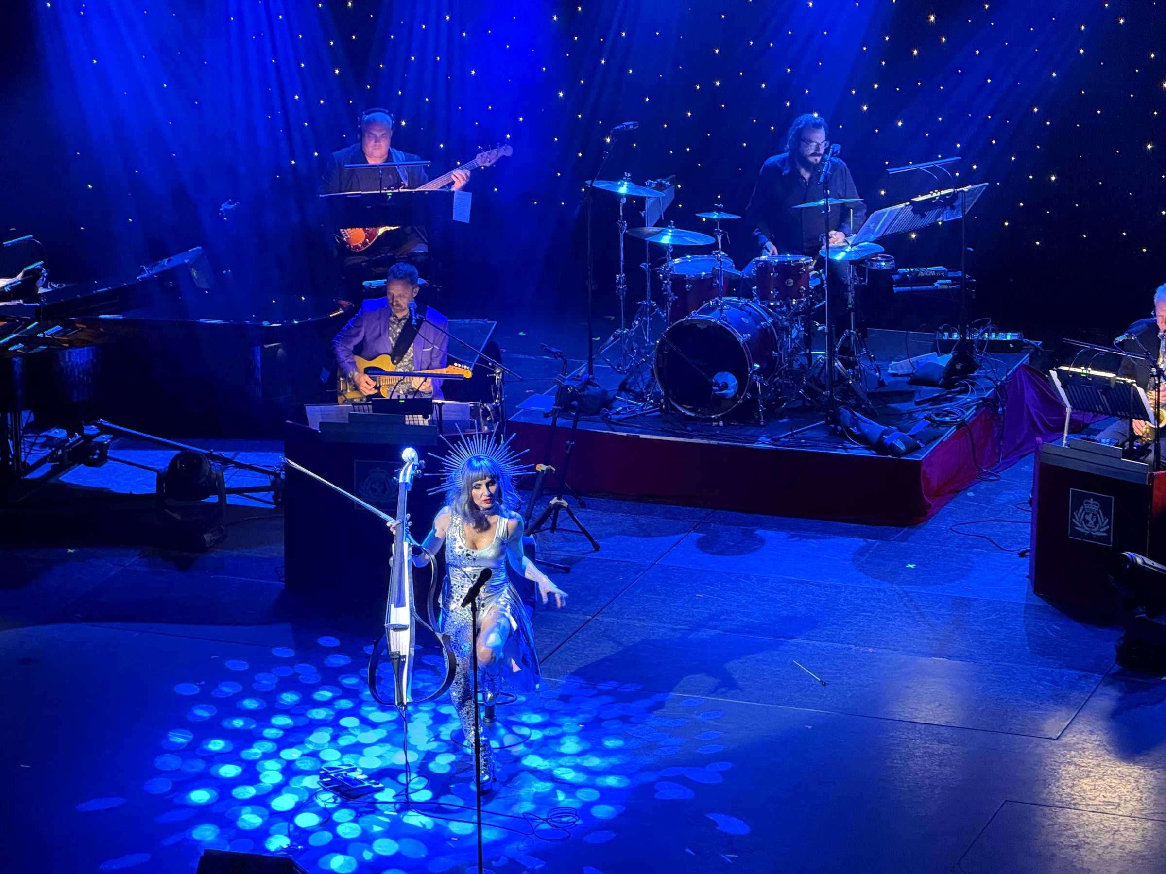 Elenka on electric cello with a live band, blue stage lights